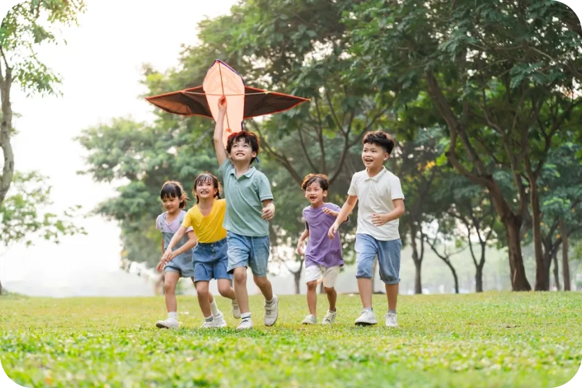 A group of children running with a kite in the air.